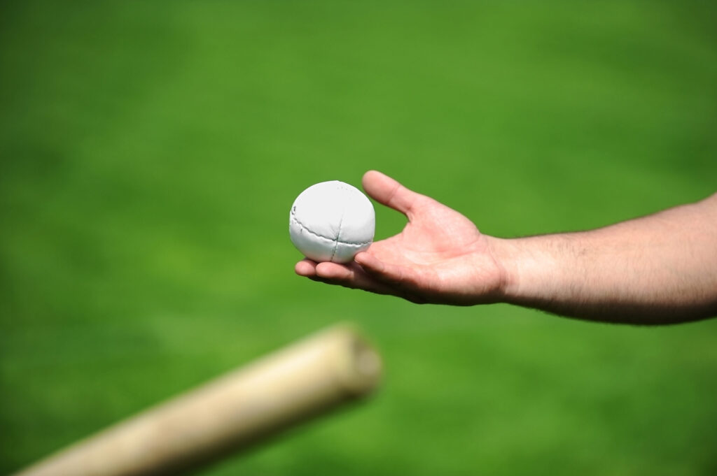 Hand Holding a Rounders Bat and Ball